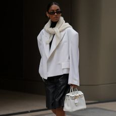 @cherifaakili wears white cropped blazer, leather shorts, white heels, scarf, bag and black sunglasses