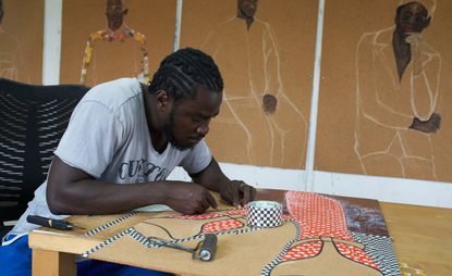 Portrait of Ghanaian artist Serge Attukwei Clottey working on a piece in his studio ahead of a show 'Beyond Skin' at Simchowitz Gallery Los Angeles