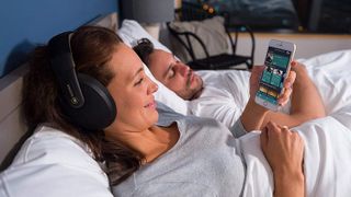 person in bed wearing Kokoon Sleep Headphones and looking at app on their phone