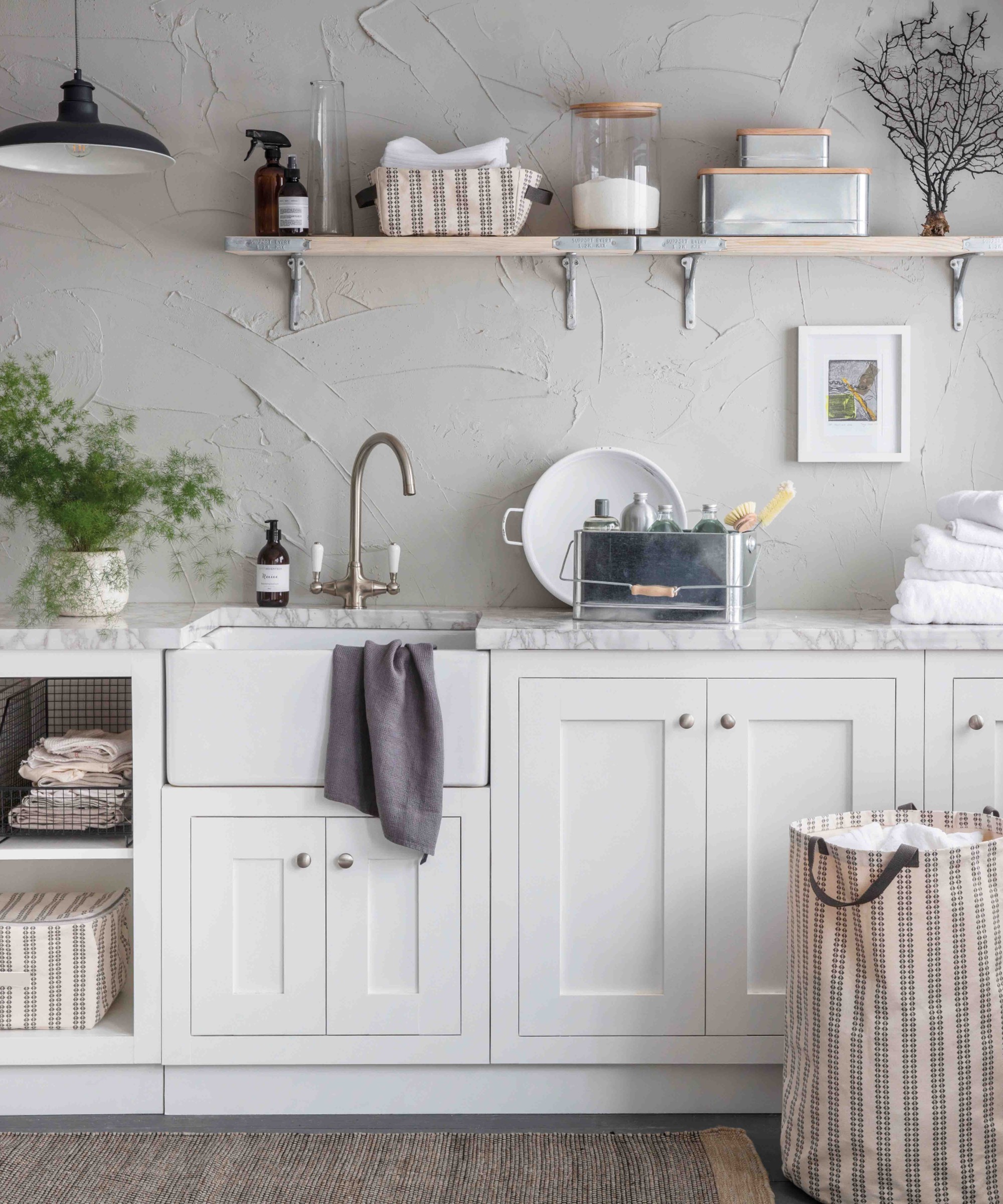 farmhouse modern laundry room with a basket, lots of linens, white cabinets and neutral walls