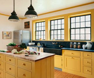 A yellow kitchen with black soapstone countertops and backsplash