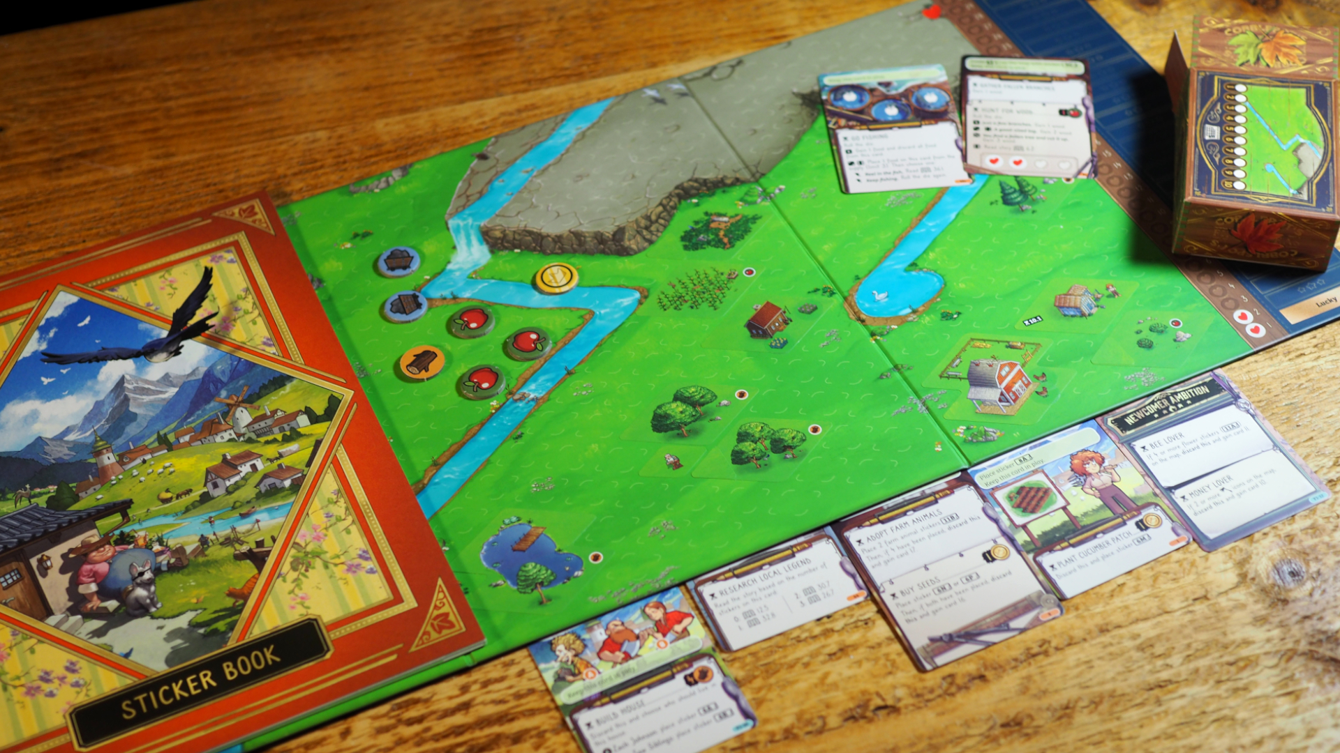 Cozy Stickerville board, cards, and components laid out on a wooden table