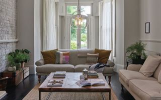 neutral living room with two sofas and large square coffee table, bay window