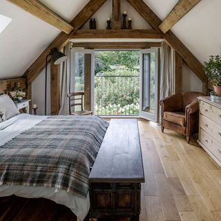 attic bedroom with leather armchair and wooden flooring