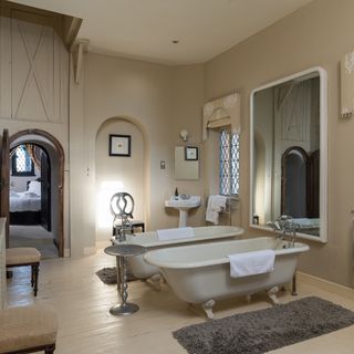 off white bathroom with two white ceramic bath tubs and a large mirror