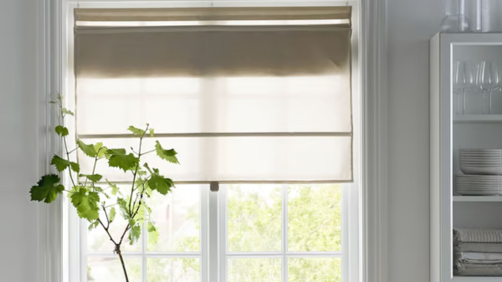 Neutral linen blind on kitchen window with shelving and tableware on right