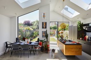 A open plan kitchen and dining room with floating island in a house extension with lots of light and windows