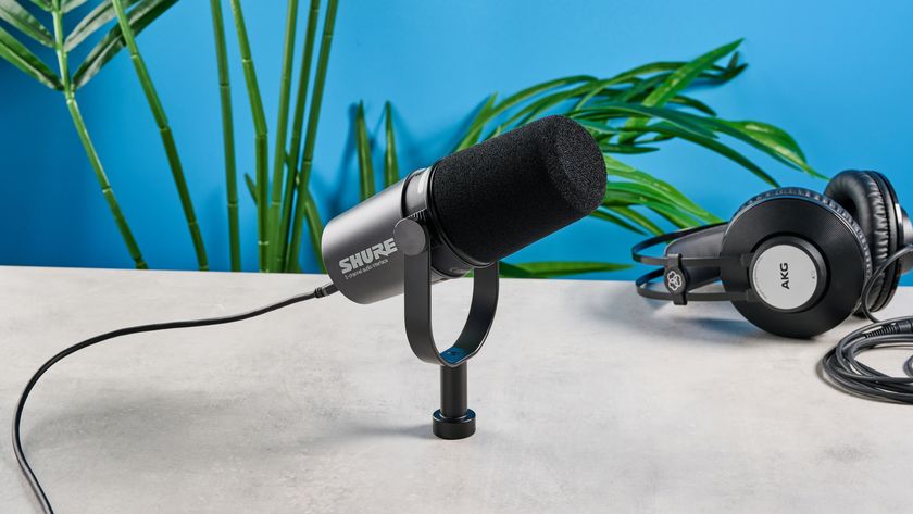 the shure mv7i, a black microphone with a black muff, touch LED pad, XLR connection and TRS input and USB-C input at the rear, photograhped against a blue tom&#039;s guide background with a pair of over-ear wired headphones 