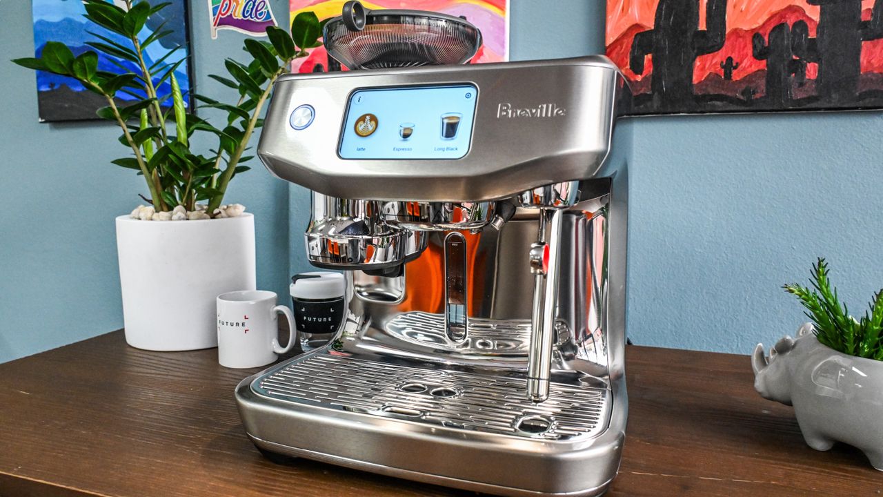 A slightly acute front-on image of the Breville Oracle Jet coffee machine sitting on a brown wooden table.
