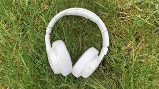 the jbl tune 750btnc headphones in white pictured on a grass background