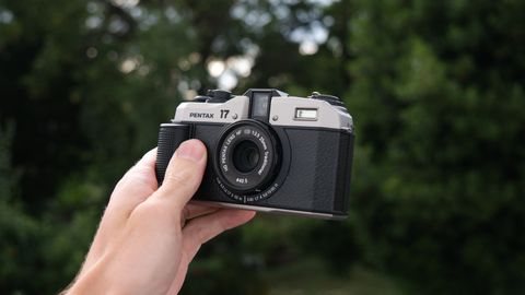 A Pentax 17 film camera held in a hand outside