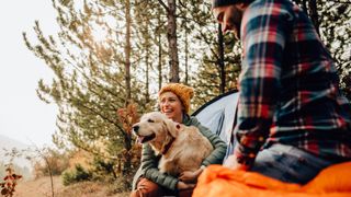 A young couple and their dog camping in the woods on a beautiful autumn day