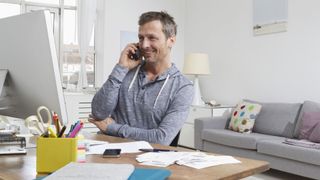 Best cordless phones 2022: image shows man talking on cordless phone in home office