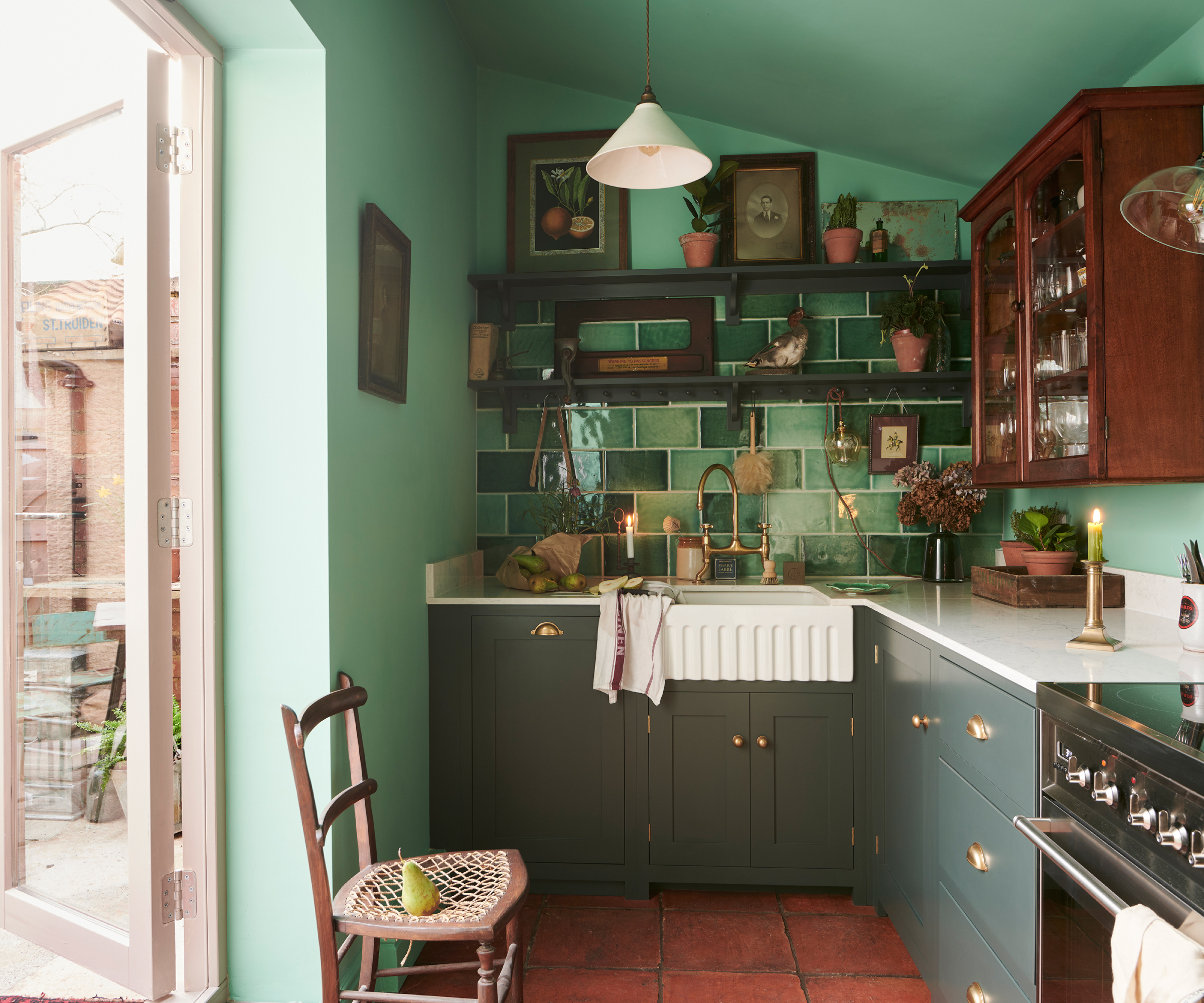 small kitchen with green cabinets, walls and tiles, french doors and vintage wooden cabinet on wall