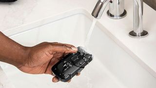 Manscaped Handyman electric shaver being rinsed under a running tap