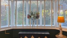 Window with blinds and flowers in a vase on the windowsill
