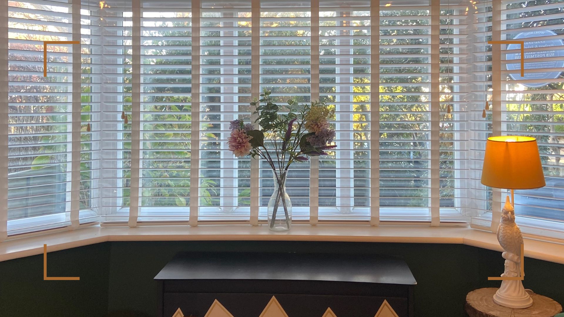 Window with blinds and flowers in a vase on the windowsill