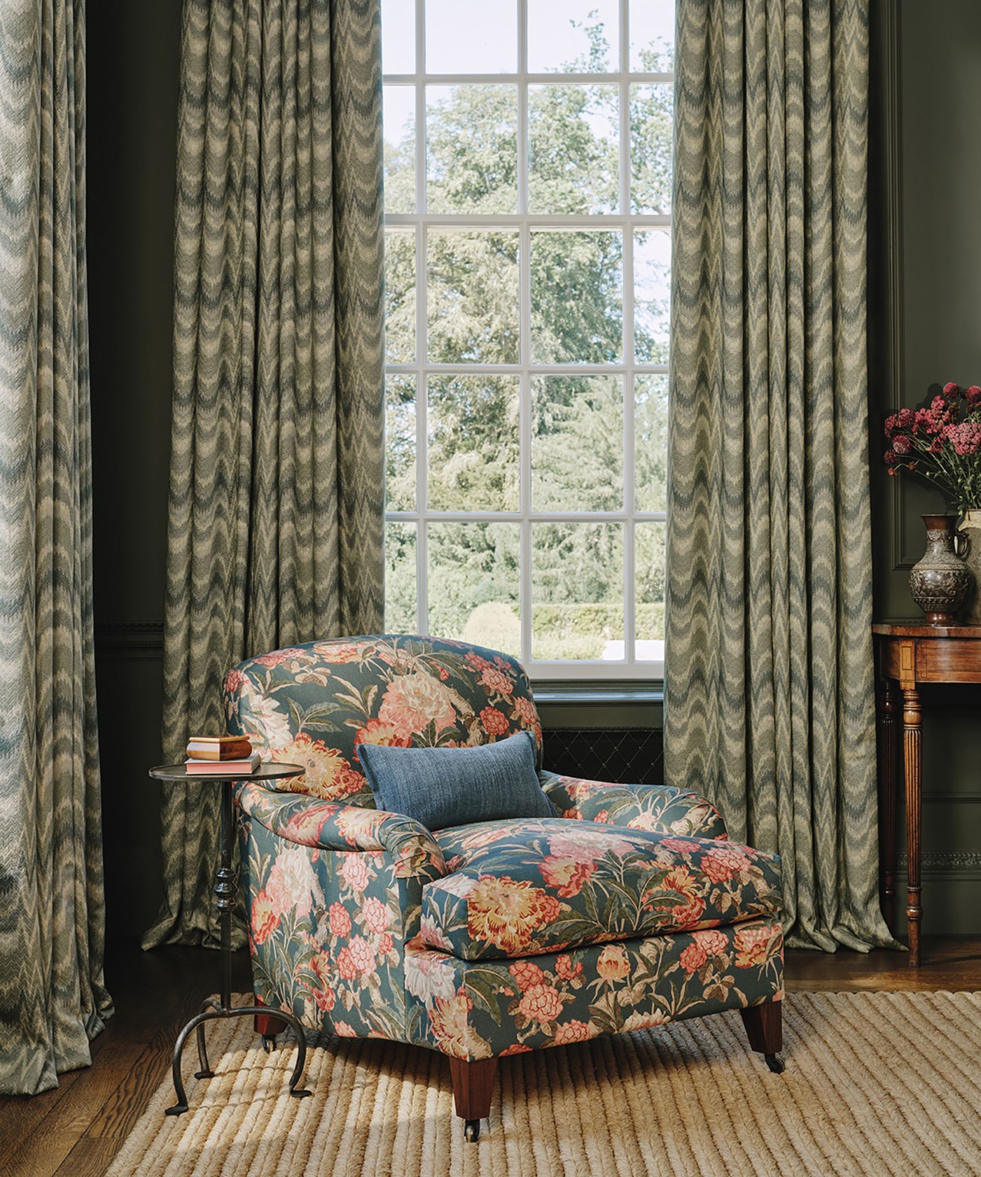 Living room with dark green walls and a floral armchair with flamestitch curtains