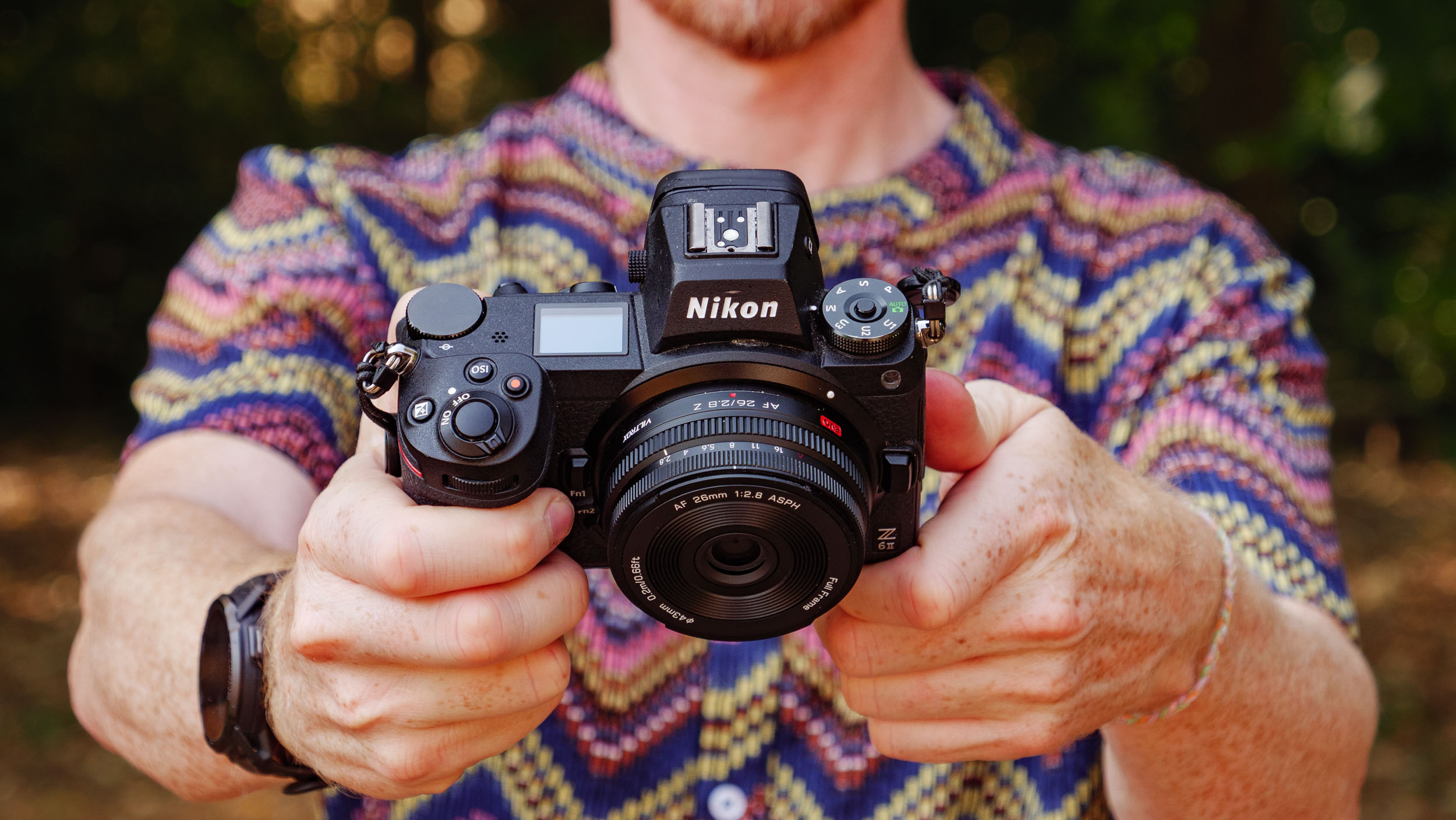 Viltrox AF 26mm F2.8 EVO 'pancake' lens attached to a Nikon mirrorless camera, photographer and TechRadar's Cameras Editor, Tim Coleman is holding the camera and is wearing a funky shirt