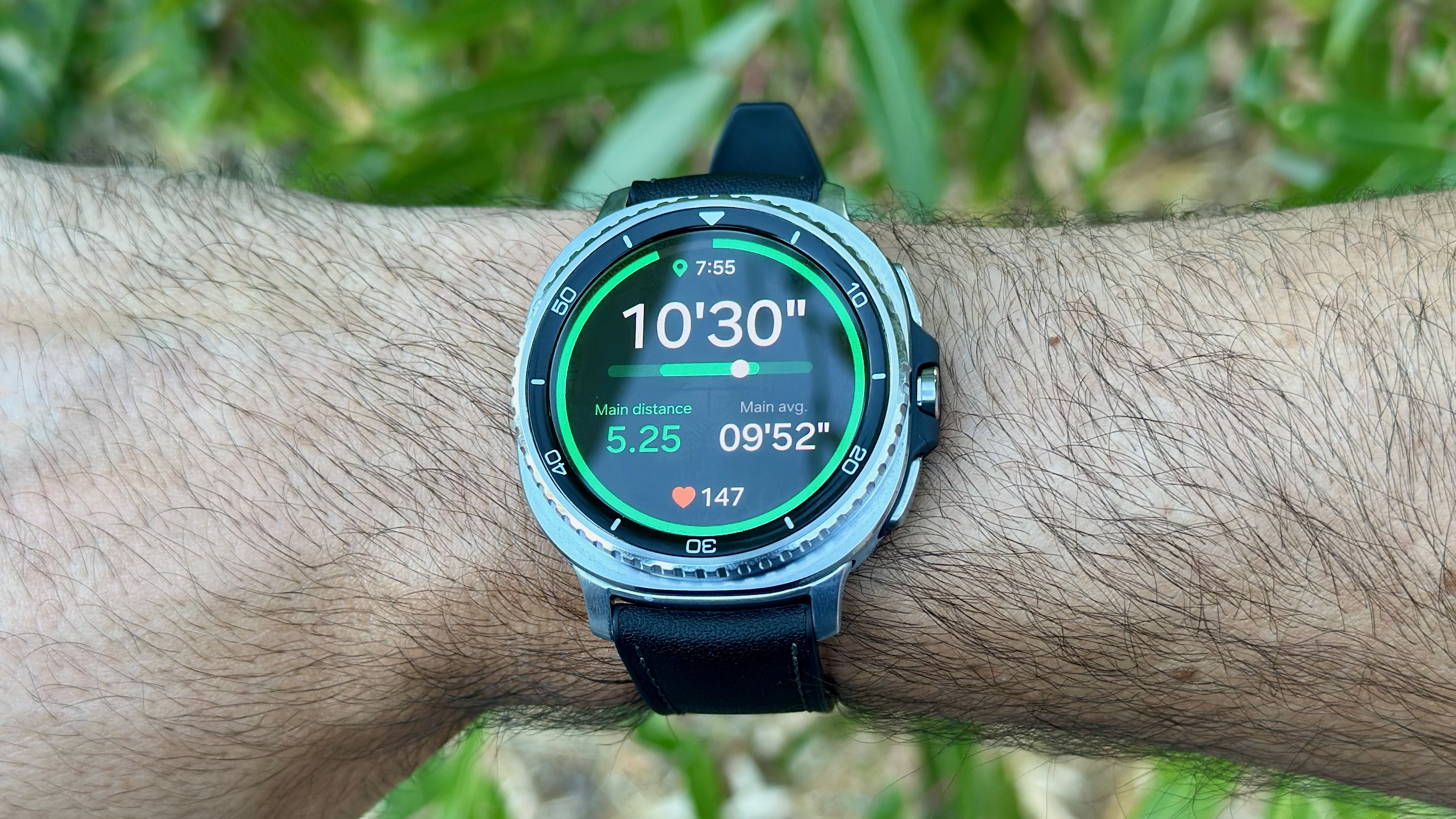 The Samsung Galaxy Watch 8 Classic on a wrist showing a Running Coach workout screen with current pace, distance, average pace, heart rate, and time.