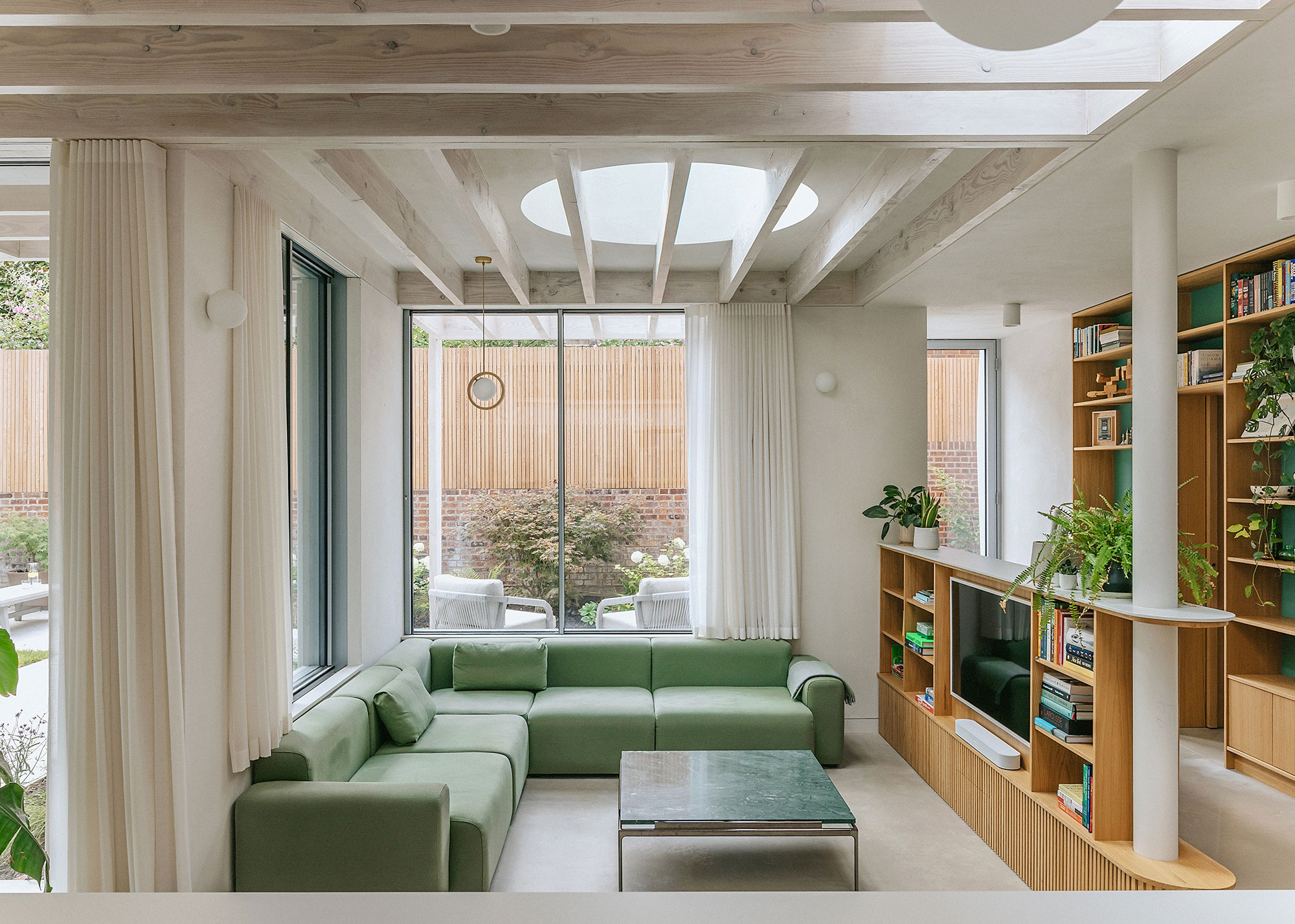 living room extension with green corner sofa with circular roof lantern