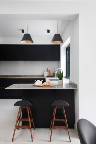 Kitchen with marble island, black cabinets and pale grey tiles