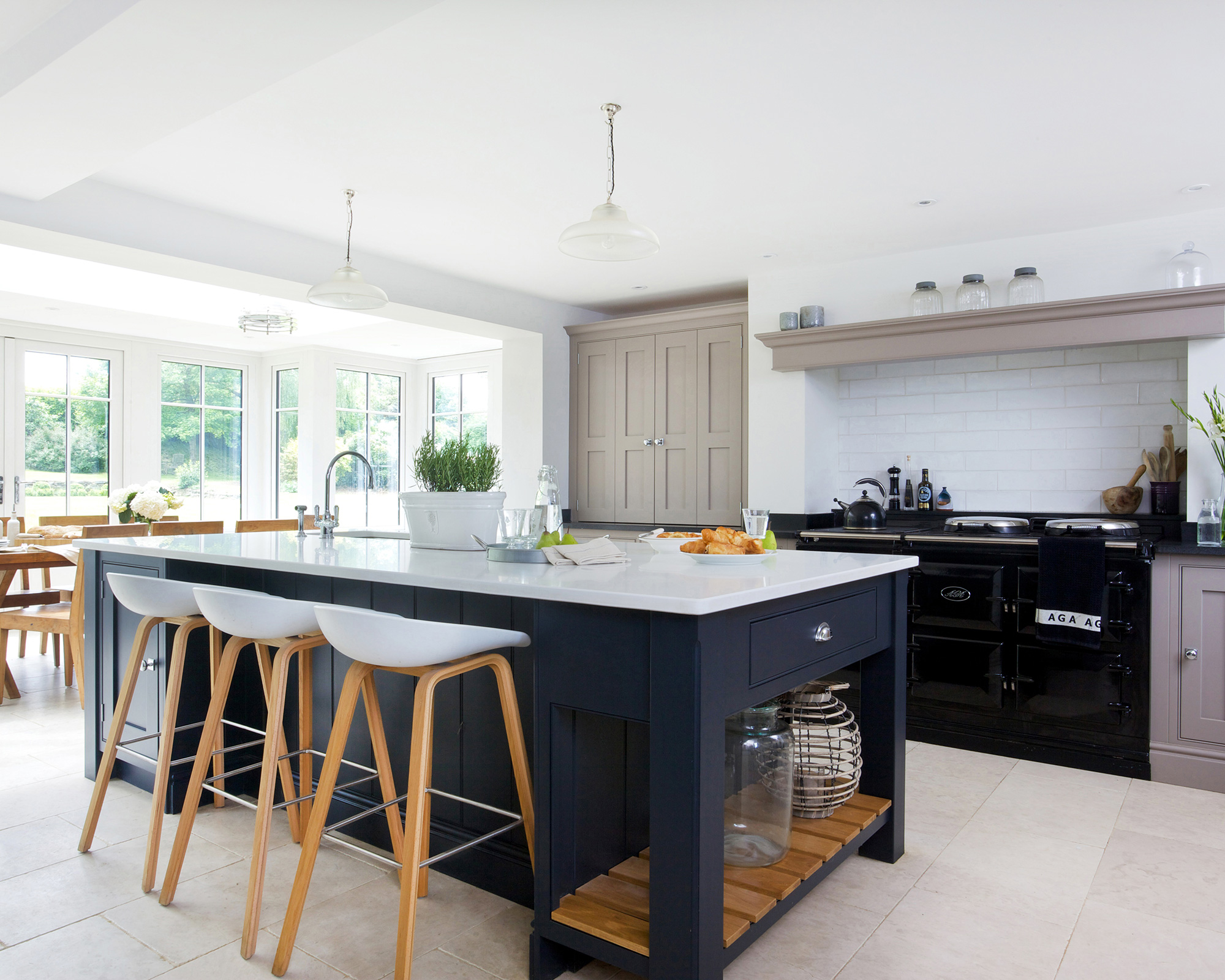 A light and airy kitchen with a large central island painted in dark blue with wooden bar stools