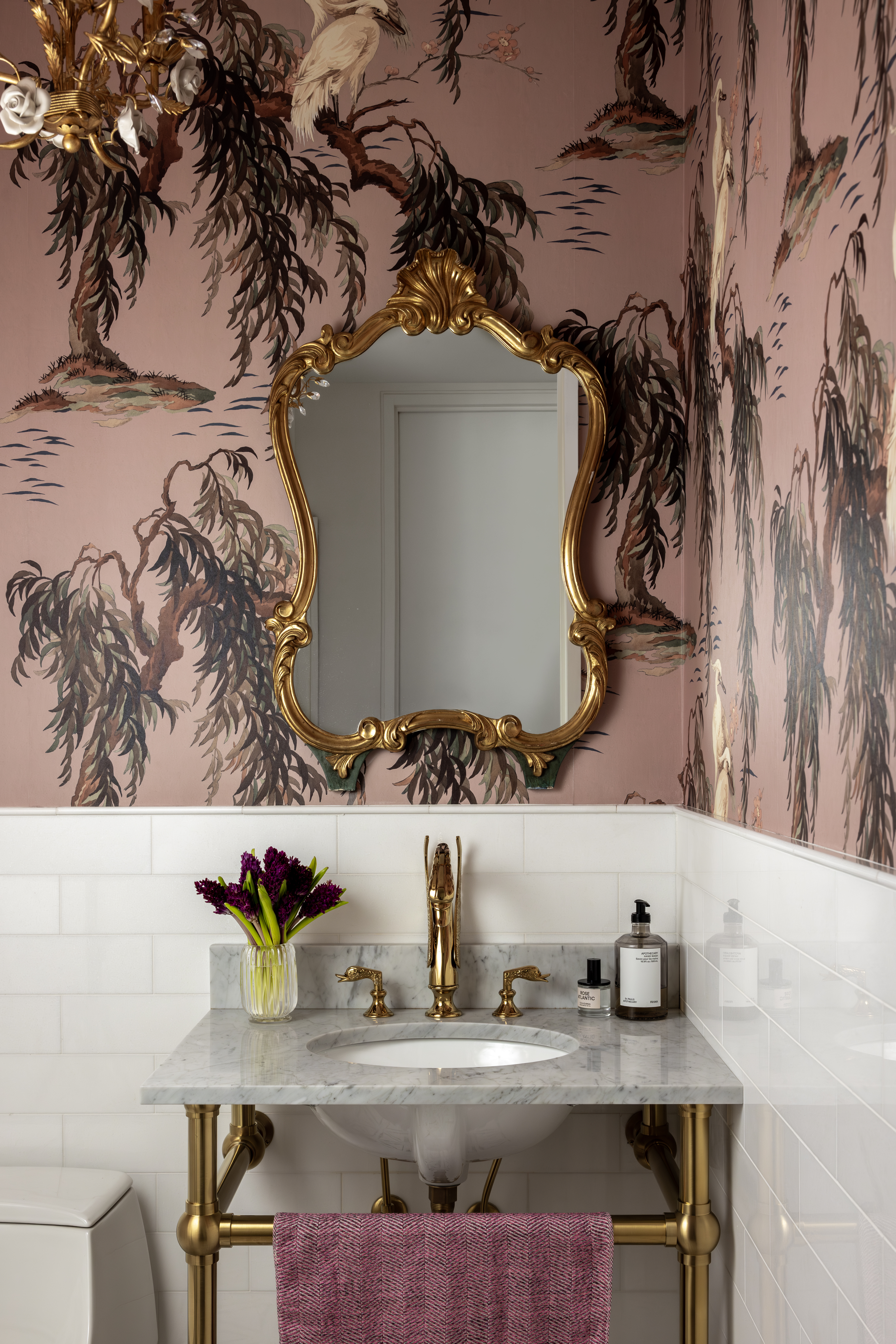 A bathroom with a pink wallpaper, and white tiles