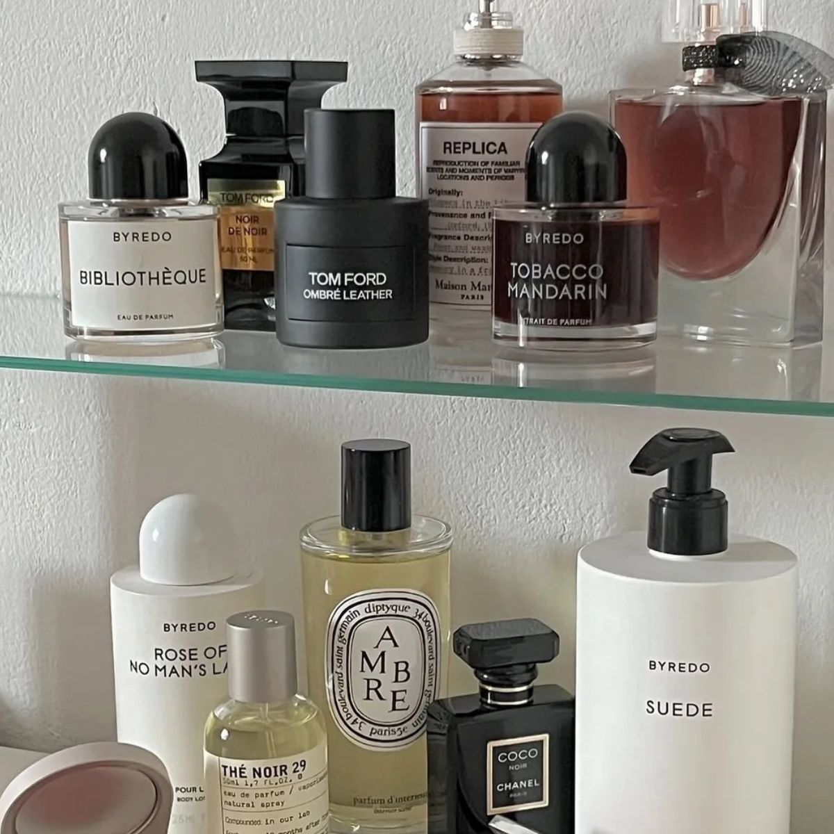 A bathroom shelf with lots of luxury perfumes on