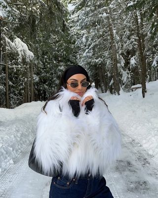 Mobina Peiman wears a white fur coat and sleek sunglasses while on a trip to Whistler, Canada.