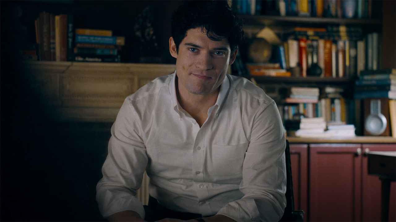 Clark Kent sitting down and smiling in 2025's Superman movie