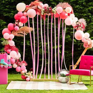 balloon arch photo booth with pink armchair for garden party and barbiecore