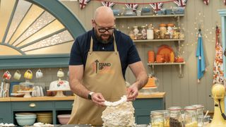 Tom Davis in a dark top and pale apron makes a meringue in The Great Celebrity Bake Off for Stand Up to Cancer