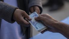 A resident receives money at a distribution site for the World Food Programme cash-assistance programme in the Qulala Pushta neighbourhood of Kabul, Afghanistan