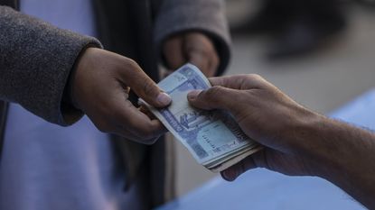 A resident receives money at a distribution site for the World Food Programme cash-assistance programme in the Qulala Pushta neighbourhood of Kabul, Afghanistan