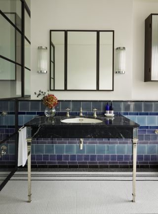 coloured tiled bathroom with black fixtures and stylish shower screen