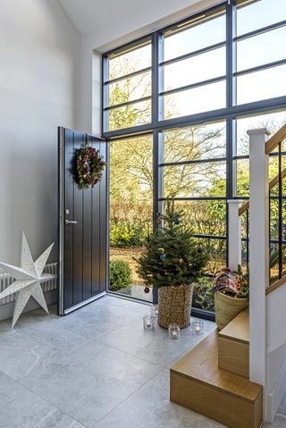 contemporary double height glazed wall entrance and open front door with christmas tree