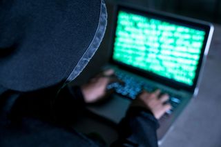 Hacker in a hood on a computer