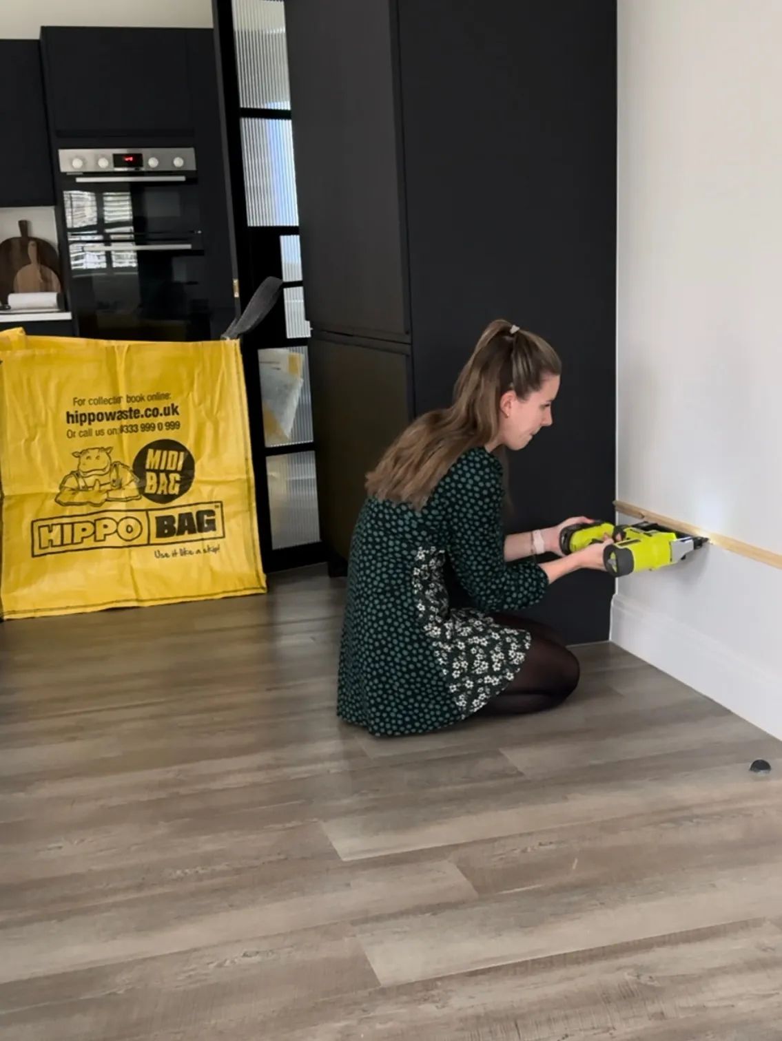 A woman drills a wooden rail up to a wall for a DIY project