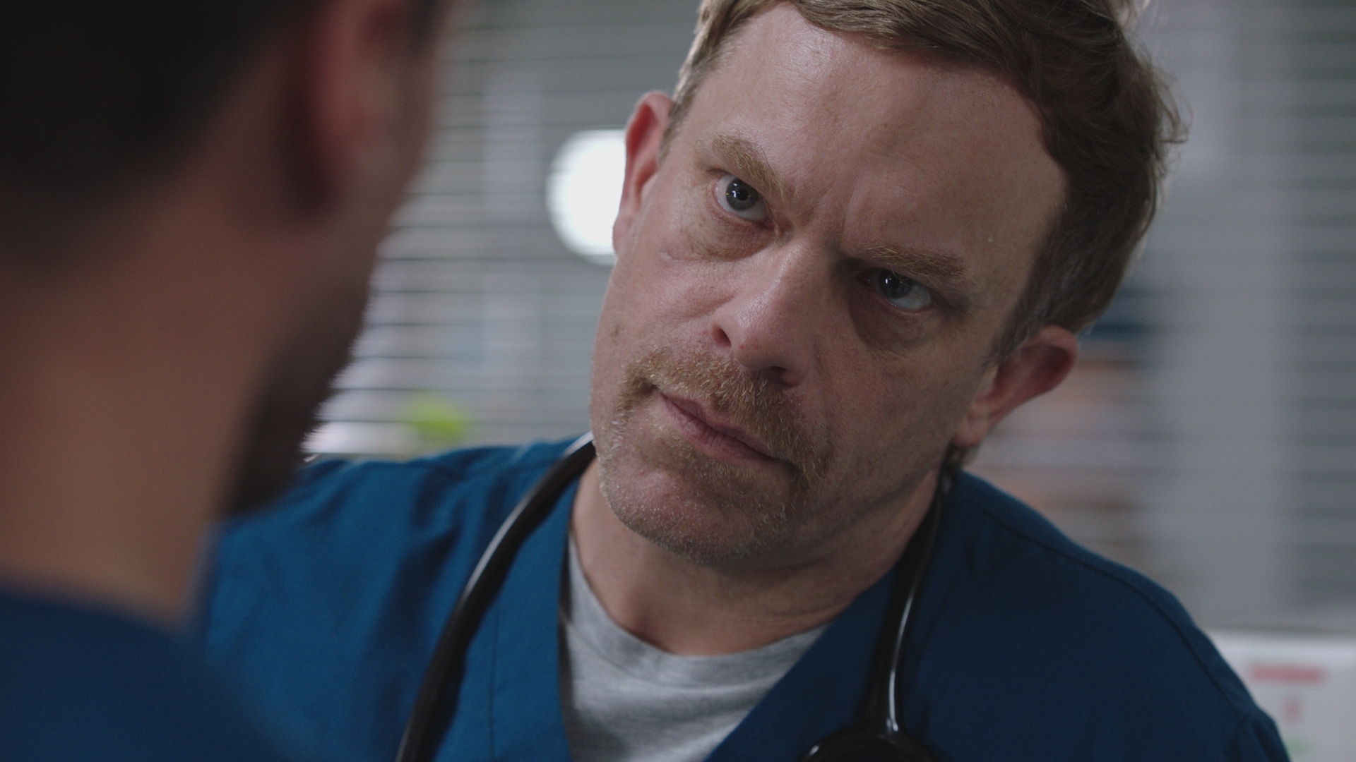 A close up of a concerned looking Dylan Keogh talking to Flynn Byron.