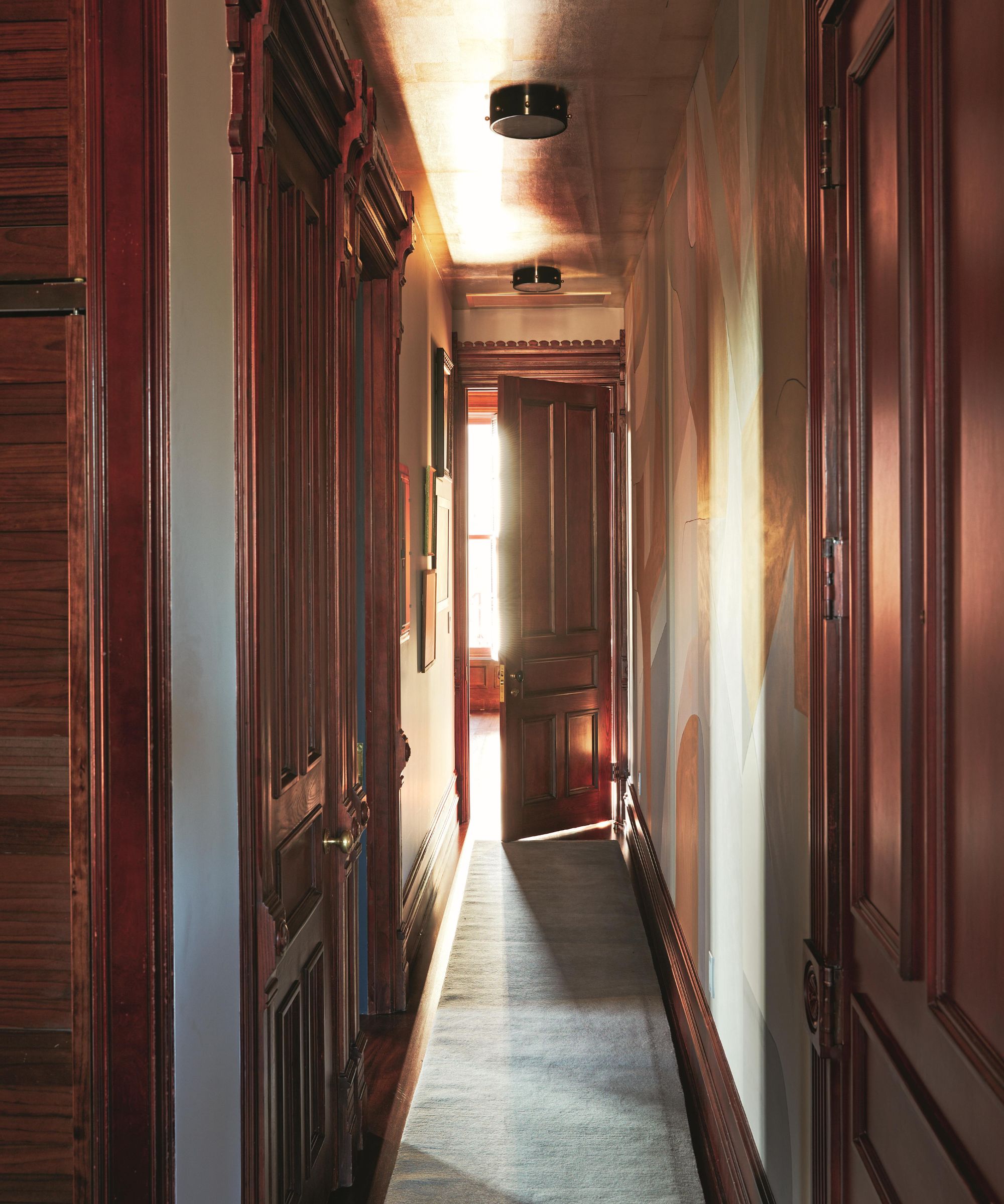 a moody hallway in a new york apartment with original mahogany architecture and doors