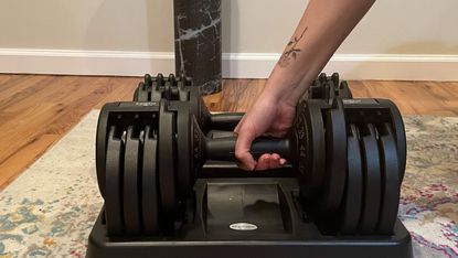 Person exercising with adjustable dumbbells at home