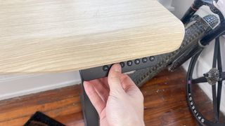 A hand adjusting the Vari Ergo standing desk's height