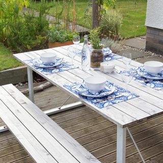 White picnic table and benches with blue patterned place settings