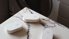 ikea klippbok water sensor on a marble background with a washing machine in the back