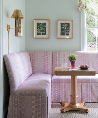 pink bench seat with small pedestal table and pale green walls