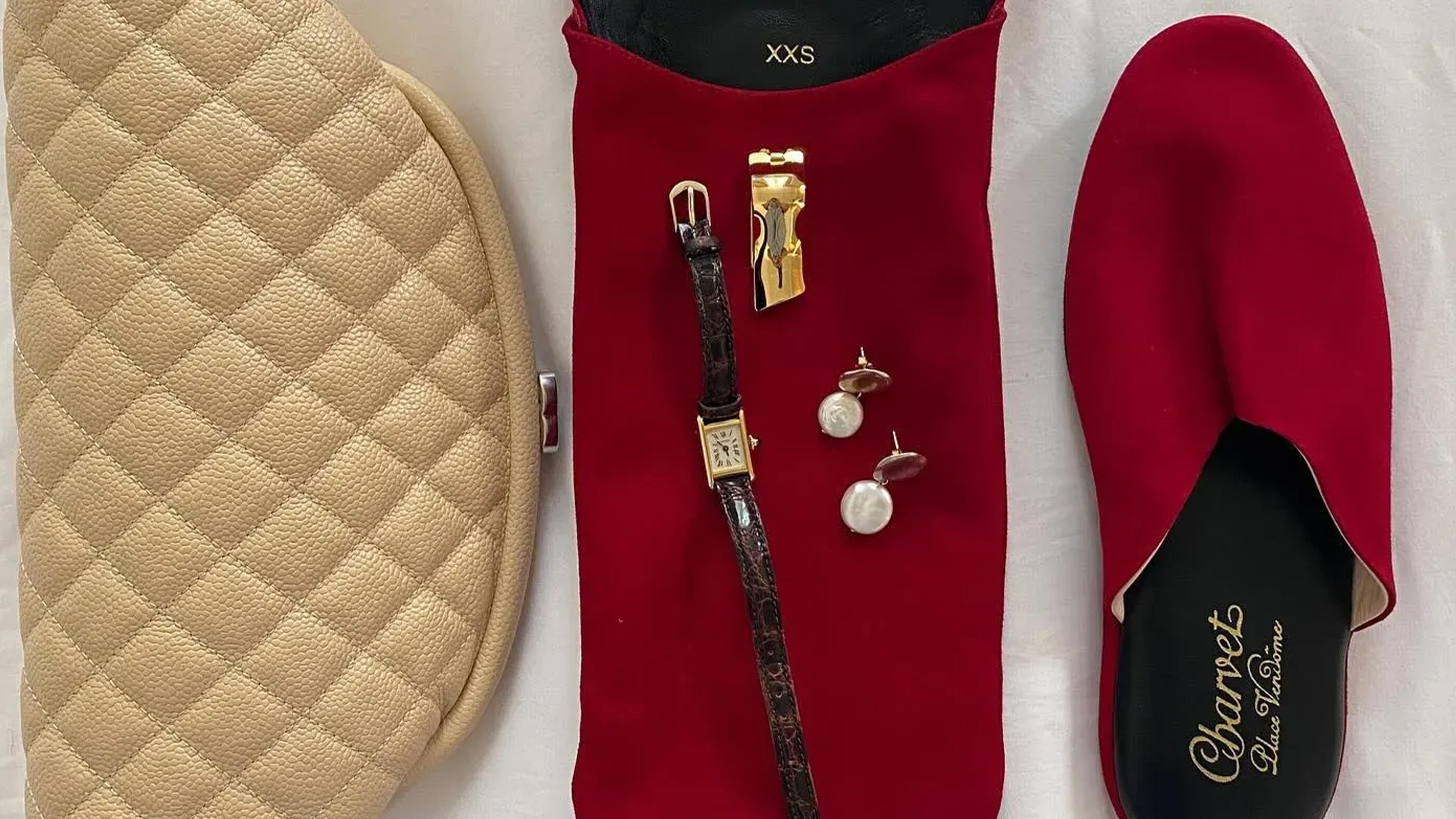 Flat lay image of red Carven slippers with pearl and watch.