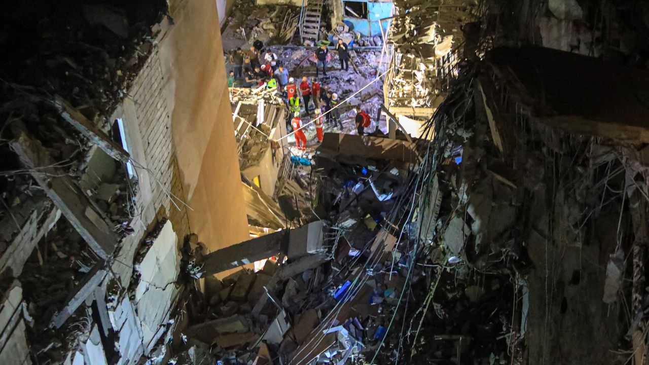 Rescuers on the street near a building with destroyed top floors following an Israeli military strike on Beirut&#039;s southern suburb