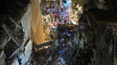 Rescuers on the street near a building with destroyed top floors following an Israeli military strike on Beirut's southern suburb