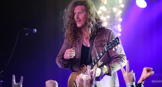 Jared James Nichols works the crowd in Nashville with his Goldtop Les Paul Standard. The stage is illuminated in purple.